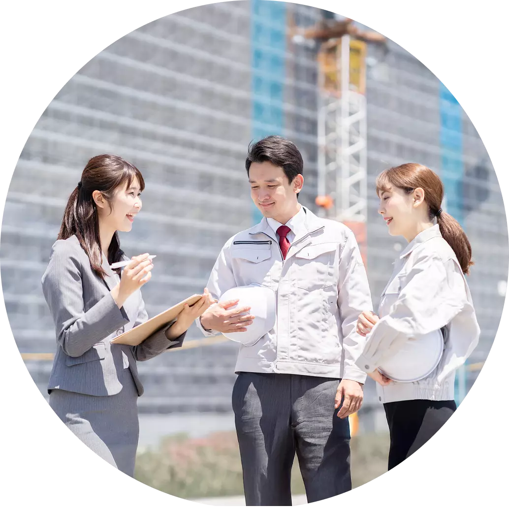 建設現場で、スーツと制服を着ている3人が話し合っている画像